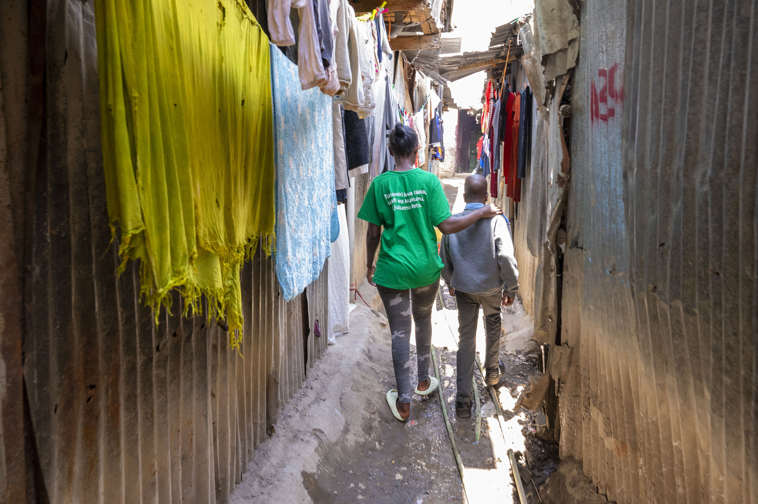 Foto 1: Sozialarbeiterin und ein auf der Straße lebender Junge im Mukuru Slum, Nairobi in Kenia. Dies ist auch das Titelbild unserer heurigen Adventsammlung.