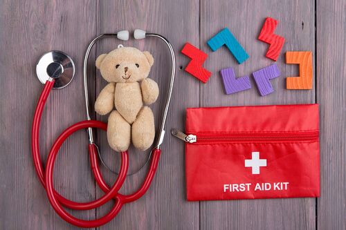 Little toy bear, stethoscope and first aid kit on the wooden desk - children health care concept, pediatrist workplace / Tovstinchuk Artem Little toy bear, stethoscope and first aid kit on the wooden desk - children health care concept, pediatrist workplace